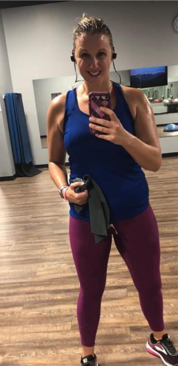 Full length shot of sweaty woman with blue tank-top in mirror